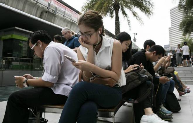 Pessoas sentadas mexendo no celular